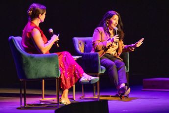 Two women seated on stage with microphones