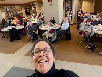 woman poses for selfie in front of seated audience