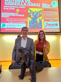 a man and a woman in front of a Godzilla statue